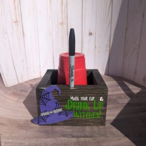 Wooden box that says drink up witches. it has red solo cups in it and has a sharpie marker in it.